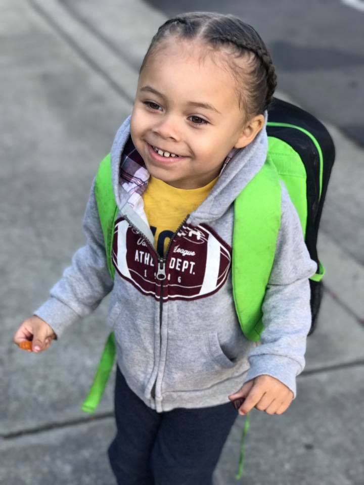 Photo of a smiling girl walking to school with her school bag on, smiling