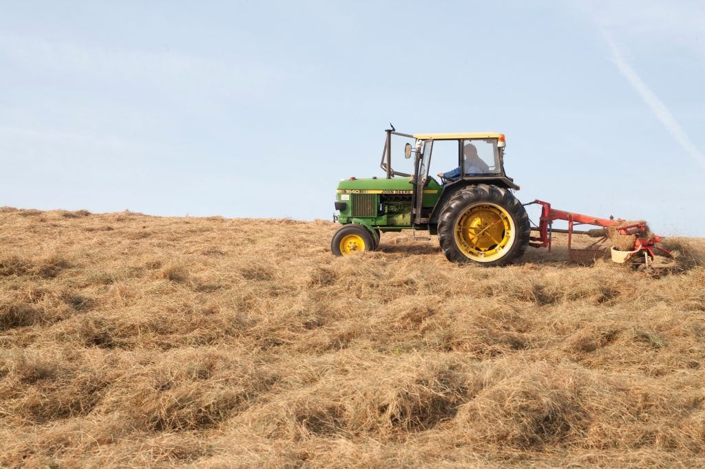 Trekker maait gras van de dijk